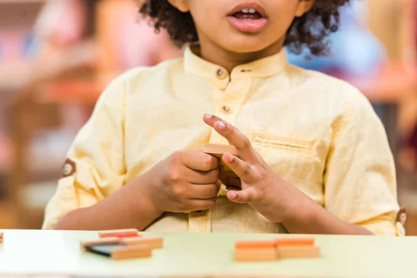 Cropped view of kid playing wooden game at table in montessori school — Stock Photo