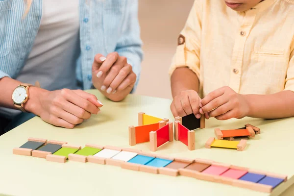 Vue recadrée d'un enfant et d'un enseignant jouant à un jeu éducatif à table pendant la leçon en classe montessori — Photo de stock