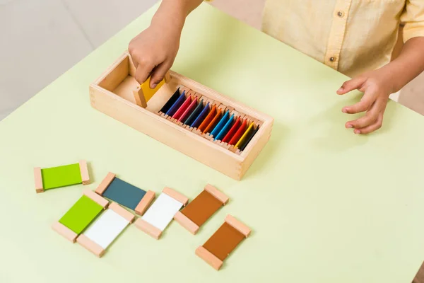 Vista ritagliata del bambino che gioca al gioco educativo con tavole colorate a tavola nella scuola montessori — Foto stock