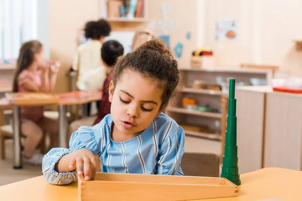 Foco seletivo da criança americana africana jogando jogo de madeira à mesa na escola montessori — Fotografia de Stock