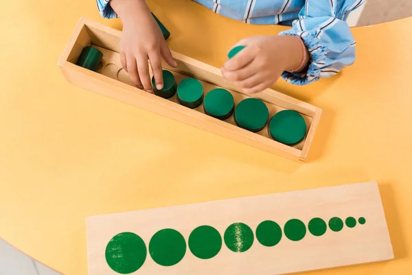 Abgeschnittene Ansicht eines Kindes mit Brettspiel aus Holz am Tisch in der Montessori-Schule — Stockfoto