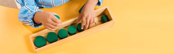 Vista de ángulo alto del niño jugando juego educativo de madera en la escuela montessori, tiro panorámico - foto de stock