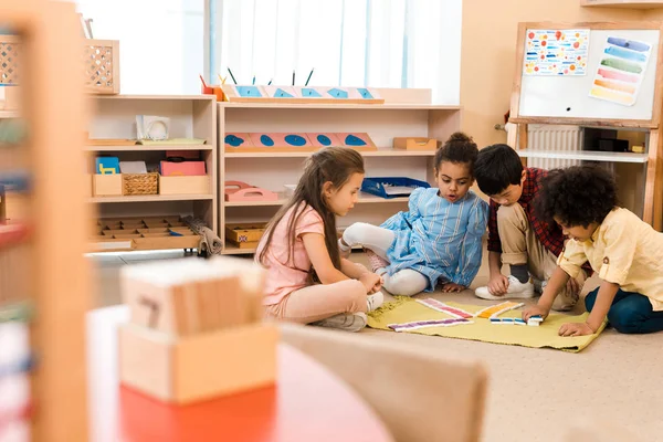 Concentration sélective des enfants jouant au jeu sur le sol à l'école montessori — Photo de stock