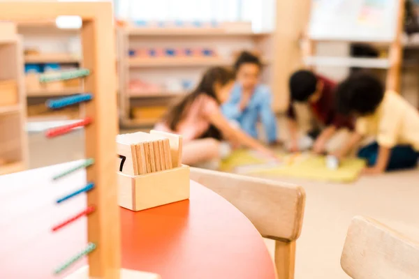 Selective focus of wooden games with playing children at background in montessori school — Stock Photo