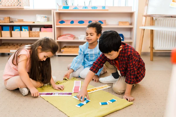 Enfants jouant à un jeu éducatif sur le sol à l'école montessori — Photo de stock