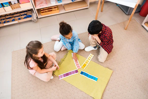 Вид зверху на дітей, які грають в навчальну гру на підлозі в класі Монтессорі — стокове фото