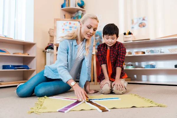 Selektiver Fokus asiatischer Kinder beim pädagogischen Spiel mit dem Lehrer auf dem Boden in der Montessori-Schule — Stockfoto