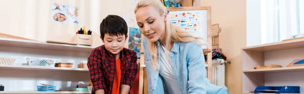 Panoramic shot of child and teacher in montessori school — Stock Photo