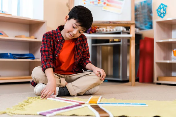 Selektiver Fokus des Kindes Falten buntes Spiel auf dem Boden in Montessori-Schule — Stockfoto