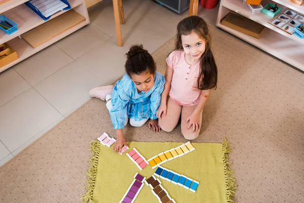 Vista aérea de los niños jugando colorido juego en el suelo en la escuela montessori - foto de stock