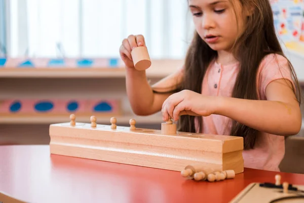 Niño jugando juego educativo de madera en la escuela montessori - foto de stock