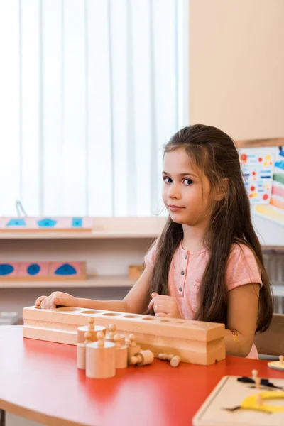 Kind faltet Lernspiel und schaut in Montessori-Schule in die Kamera — Stockfoto
