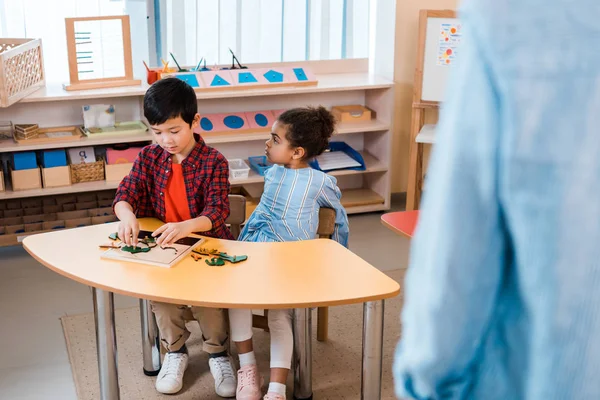 Enfoque selectivo de los niños y el maestro durante la lección en la escuela montessori - foto de stock