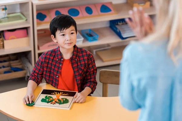 Selettivo fuoco di asiatico ragazzo guardando insegnante in montessori scuola — Foto stock