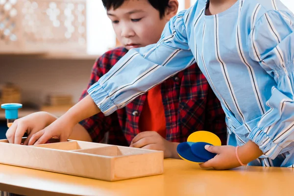 Selektiver Fokus der Kinder mit Sanduhr und Lernspiel am Tisch in der Montessori-Schule — Stockfoto