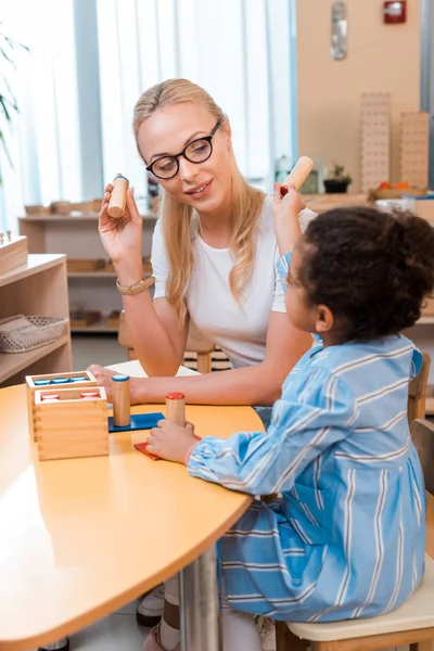 Criança e professor jogando jogo de tabuleiro de madeira na mesa na escola montessori — Fotografia de Stock