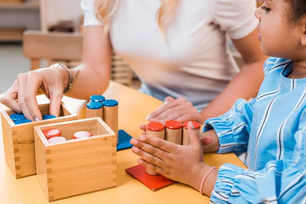 Focus selettivo di bambini e insegnanti che giocano al gioco educativo alla scrivania nella scuola montessori — Foto stock