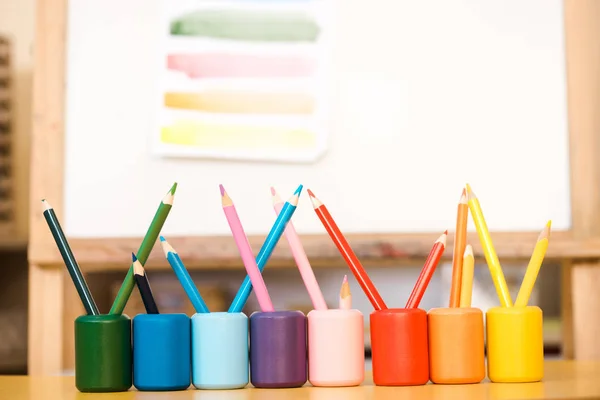 Selective focus of colorful pencils on table with drawn on board at background — Stock Photo