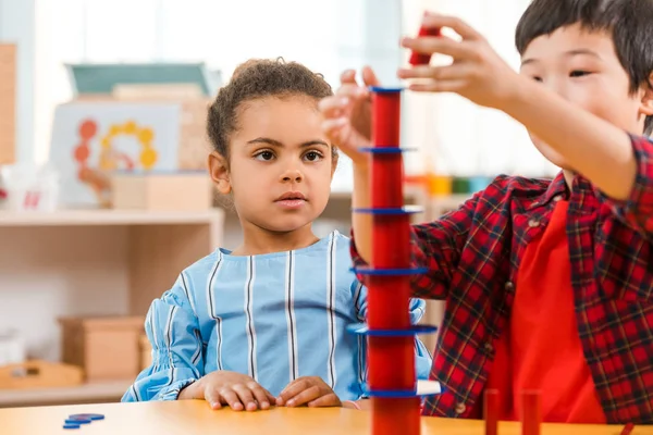 Concentration sélective des enfants jouant au jeu pendant les cours à l'école montessori — Photo de stock