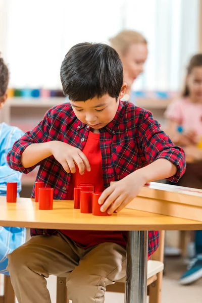Foco seletivo de criança asiática jogo educativo dobrável com professor e crianças em segundo plano na classe montessori — Fotografia de Stock