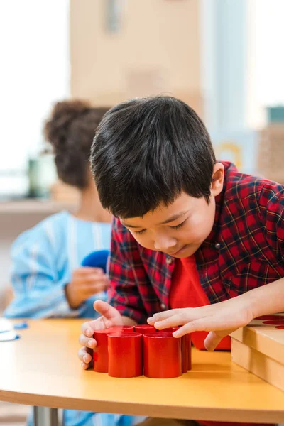 Selective focus of asian child playing wooden game by kid during lesson in montessori school — Stock Photo