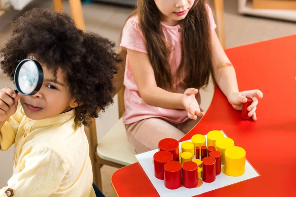 Vista ad alto angolo dei bambini con gioco educativo e lente d'ingrandimento in classe montessori — Foto stock