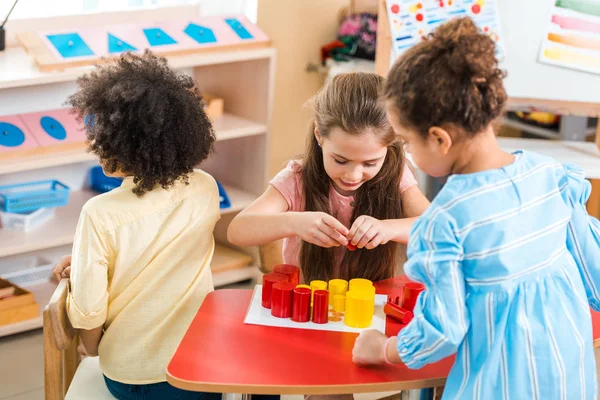 Bambini che giocano a colorati giochi educativi alla scrivania nella scuola montessori — Foto stock