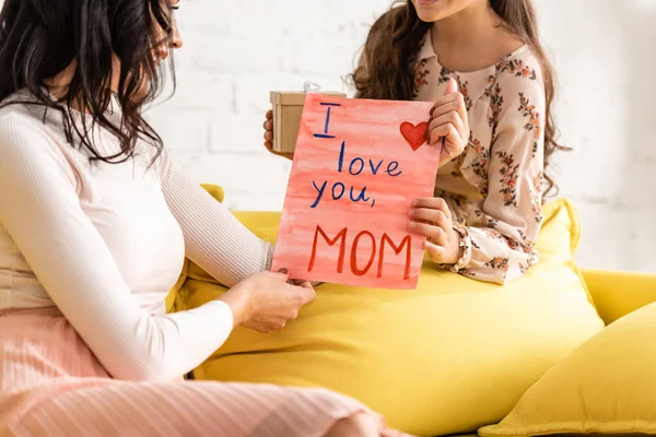Cropped view of child presenting mothers day card with i love you mom inscription to mother — Stock Photo