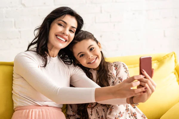 Feliz madre e hija sonriendo a la cámara mientras toma selfie en el día de las madres - foto de stock
