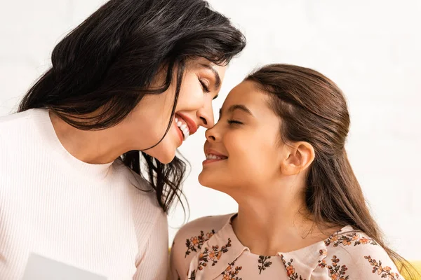 Feliz mamá y su hija sonriendo cara a cara con los ojos cerrados en el día de las madres - foto de stock