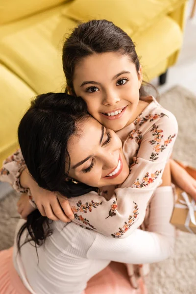 Vista aérea de niño alegre mirando a la cámara mientras abraza feliz mamá en el día de las madres - foto de stock