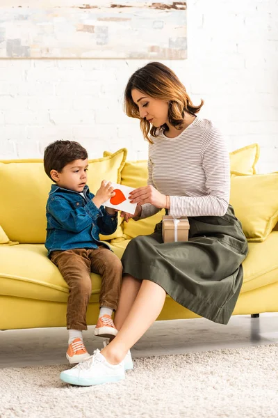 Carino bambino presentando madri scheda giorno con il simbolo del cuore per la mamma felice — Foto stock