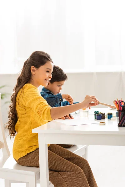 Adorable brother and sister sitting at table and drawing together — Stock Photo