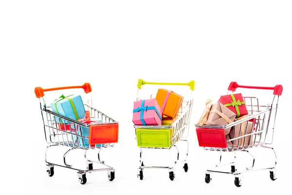 Pequeños carritos de compras decorativos con cajas de regalo aisladas en blanco - foto de stock
