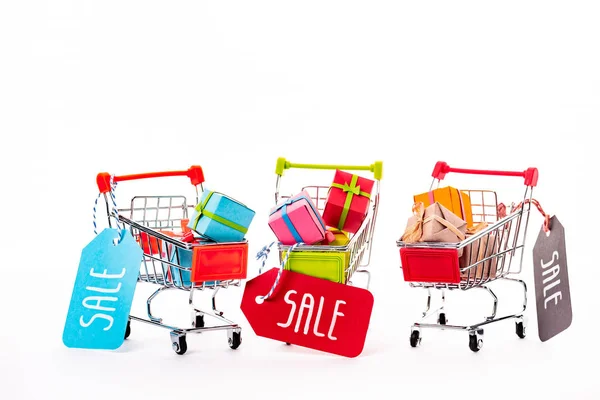 Decorative small shopping carts with gift boxes and price tags with sale lettering isolated on white — Stock Photo