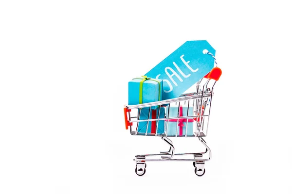 Decorative small shopping cart with gift boxes and price tag with sale lettering isolated on white — Stock Photo