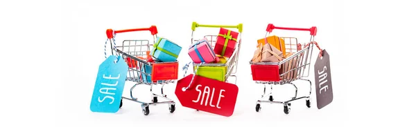 Dekorative kleine Einkaufswagen mit Geschenkschachteln und Preisschildern mit Verkaufsbuchstaben isoliert auf weißer, panoramischer Aufnahme — Stockfoto