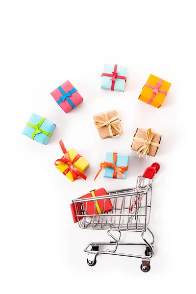 Top view of decorative small shopping cart near gift boxes isolated on white — Stock Photo
