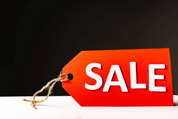 Red price tag with sale lettering isolated on black — Stock Photo