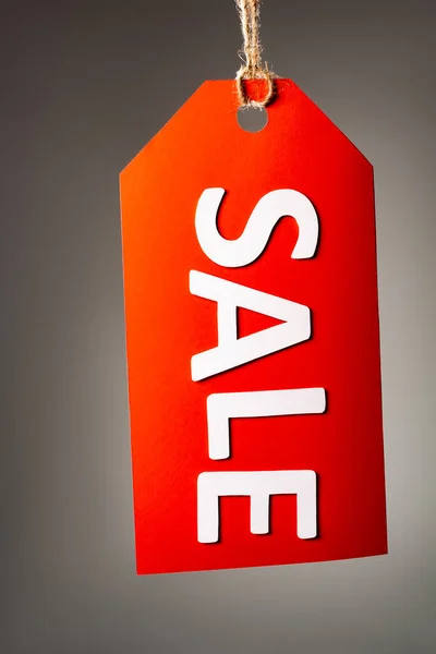 Red price tag with sale lettering on black background — Stock Photo