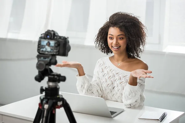 Selective focus of cheerful african american video blogger in braces gesturing near digital camera — Stock Photo
