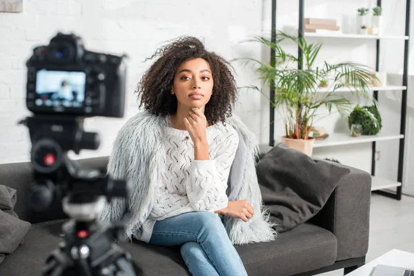 Selective focus of beautiful african american influencer looking at digital camera while sitting on sofa — Stock Photo
