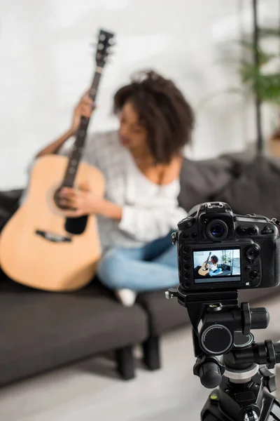 Mise au point sélective de l'appareil photo numérique avec jeune fille afro-américaine jouant de la guitare acoustique sur l'écran — Photo de stock