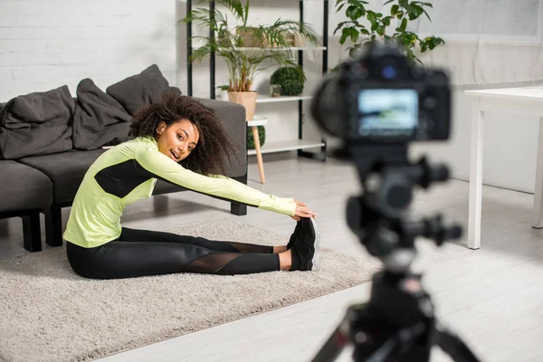 Enfoque selectivo de alegre afroamericano video blogger en frenillos ejercicio cerca de la cámara digital - foto de stock