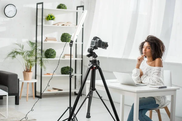 Pensive african american influencer thinking near digital camera — Stock Photo