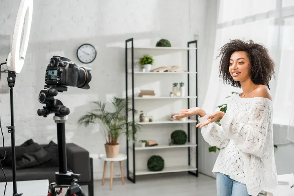 Cheerful african american influencer in braces gesturing while talking near digital camera — Stock Photo