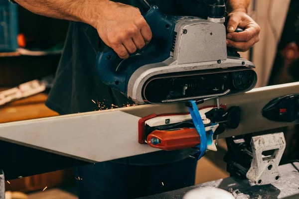 Vue recadrée du travailleur réparant le ski avec une ponceuse à ceinture dans l'atelier de réparation — Photo de stock