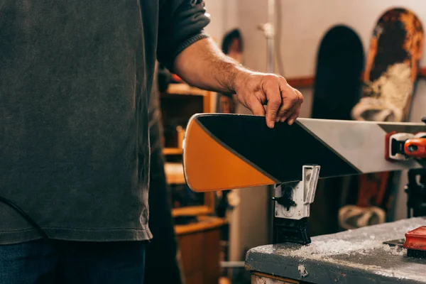 Cropped view of worker touching ski in repair shop — Stock Photo