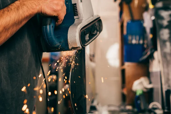 Vue recadrée du travailleur réparant le snowboard avec une ponceuse à ceinture dans un atelier de réparation — Photo de stock