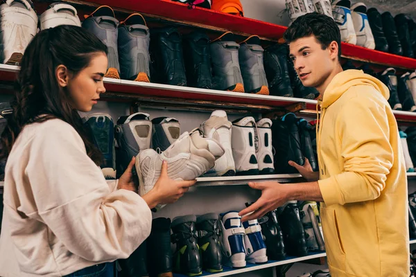 Клієнт тримає лижний черевик і розмовляє з працівником в ремонтному магазині — стокове фото